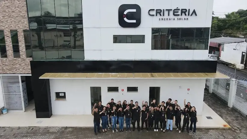 Equipe da Critéria Energia Solar diante da sede, com a marca Critéria visível no prédio